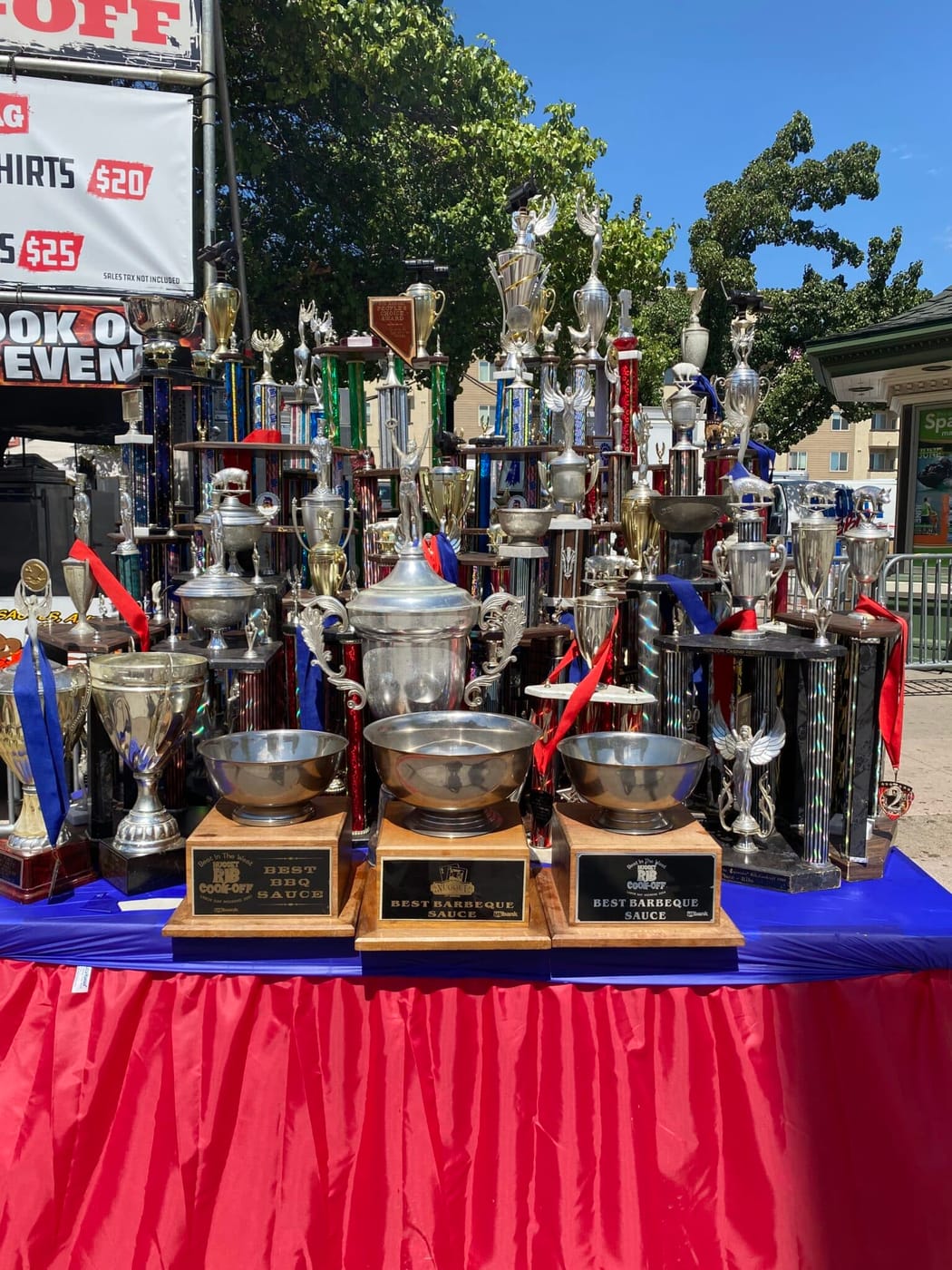 A crowded table of cook-off silverware — loving cups, statuettes and ribboned plaques — displayed at the team's booth.