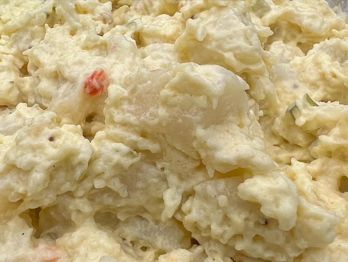 A close-up of creamy macaroni salad flecked with diced vegetables.
